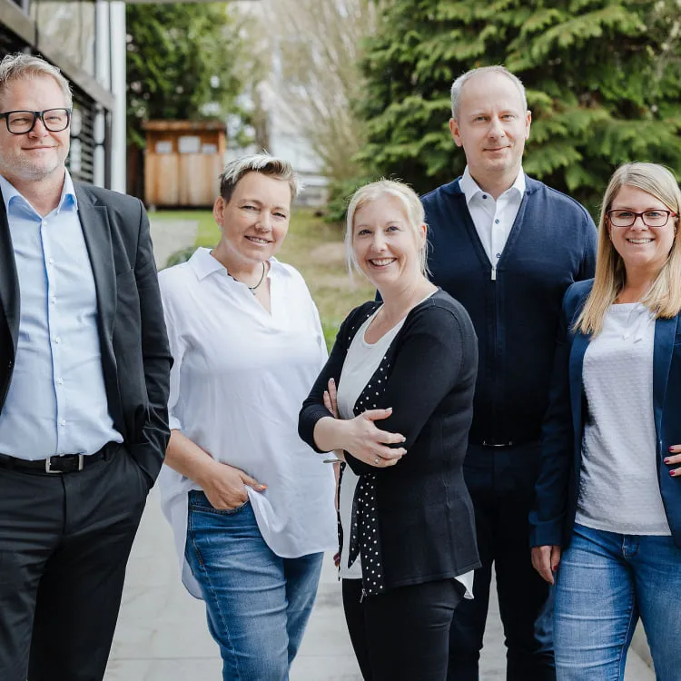 Team von Pletzer Immobilien im Freien – fünf Mitarbeitende stehen zusammen, lächeln in die Kamera und präsentieren die Unternehmensgemeinschaft.